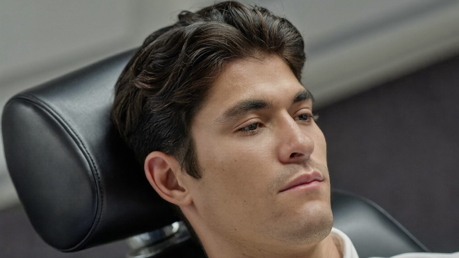 Calm man with styled dark hair resting in a reclined treatment chair