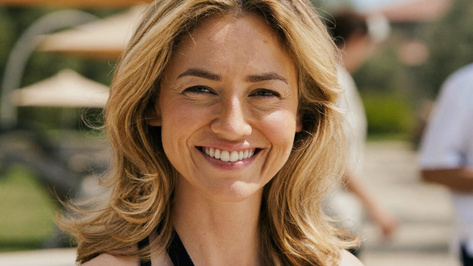 Smiling woman with thick, shoulder-length wavy hair outdoors