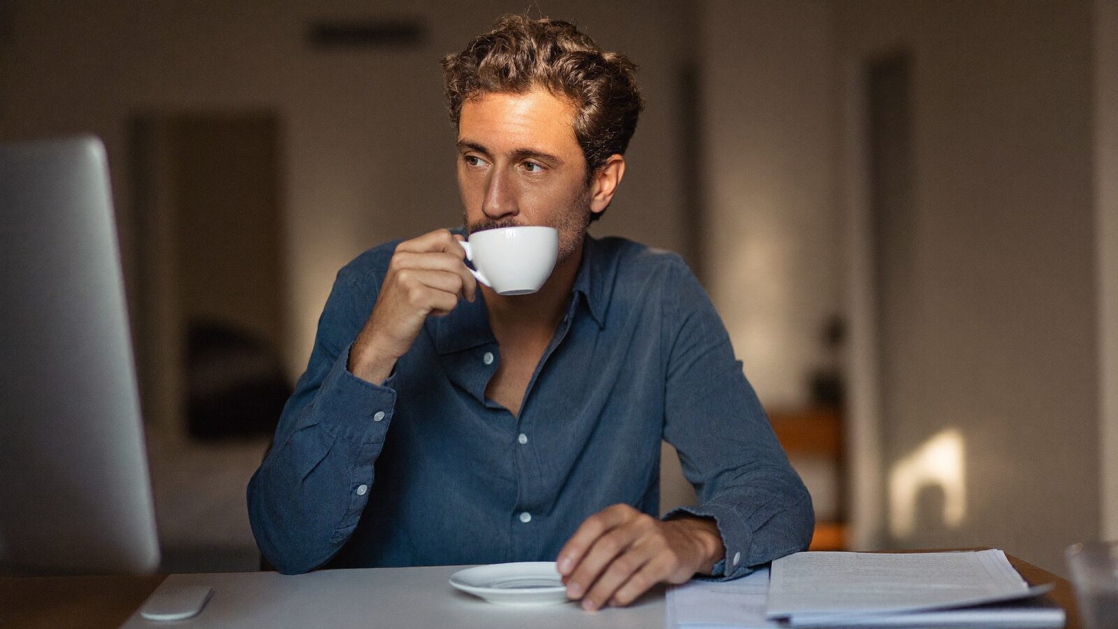 Thoughtful man drinking coffee at a home desk