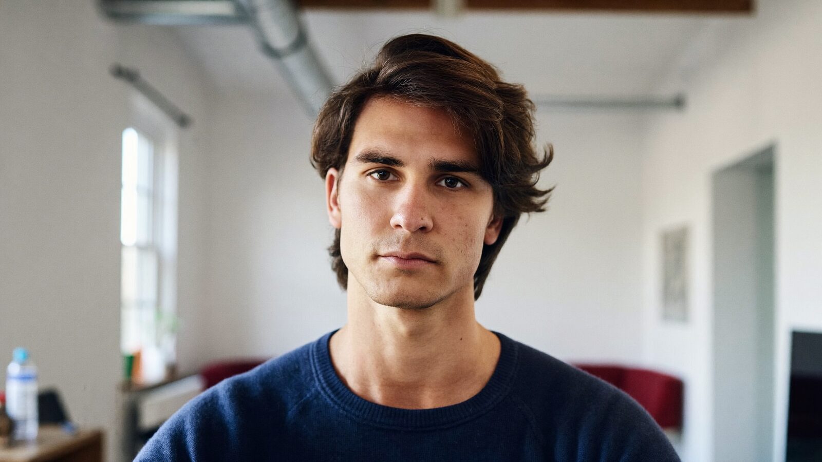 Man with natural medium-length brown hair and a well-framed hairline in a bright studio