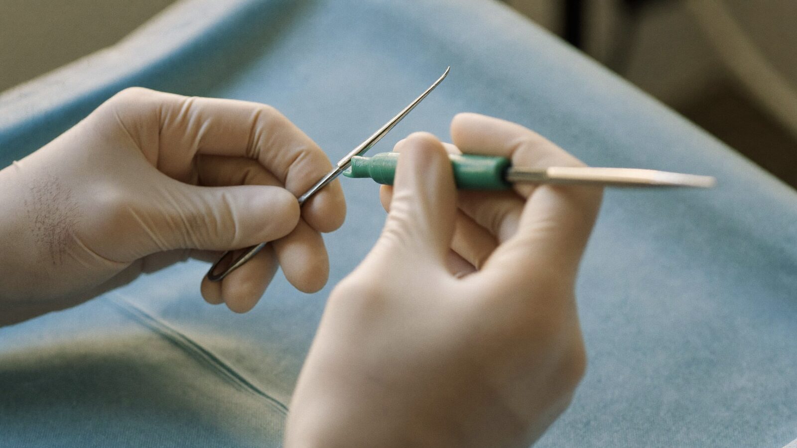 Gloved hands holding a fine handheld surgical instrument